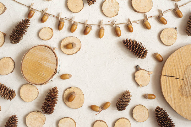 Autumn composition, frame made of pine cones, acorns and small wooden stumps. Flat lay, top view. Copy space - Φωτογραφία, εικόνα