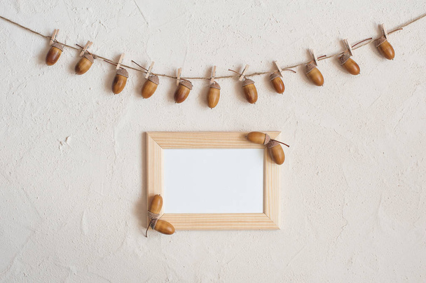 Autumn composition with wooden frame. Acorn with clothespins on clothes line rope. Wooden pegs. Flat lay, top view, copy space. - Foto, Imagen