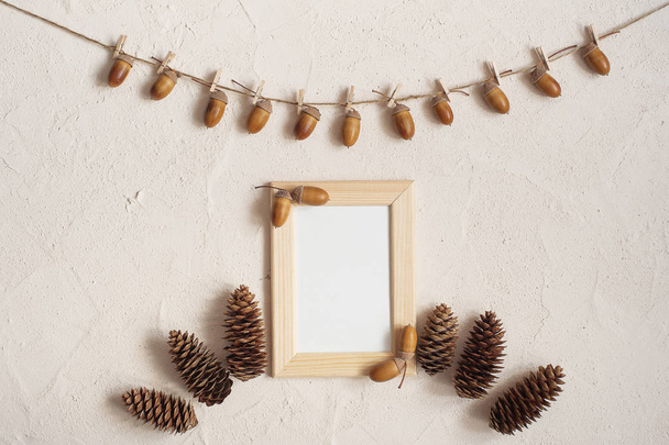 Autumn composition with wooden frame. Acorn with clothespins on clothes line rope. Wooden pegs. Flat lay, top view, copy space. - Foto, imagen
