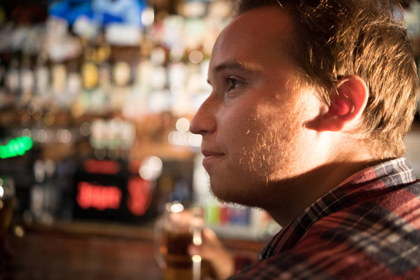 Thoughtful young man drinking beer at the bar counter - Photo, Image
