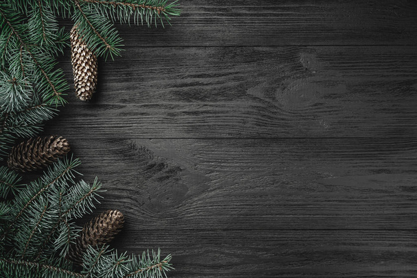 Cartão de Natal. Fundo de madeira preta com galhos e cones de abeto no lado, vista superior
 - Foto, Imagem