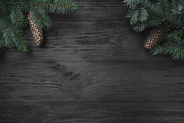 Cartão de Natal. Fundo de madeira preta, com ocreanga e cones de abeto em cantos superiores, vista superior
 - Foto, Imagem