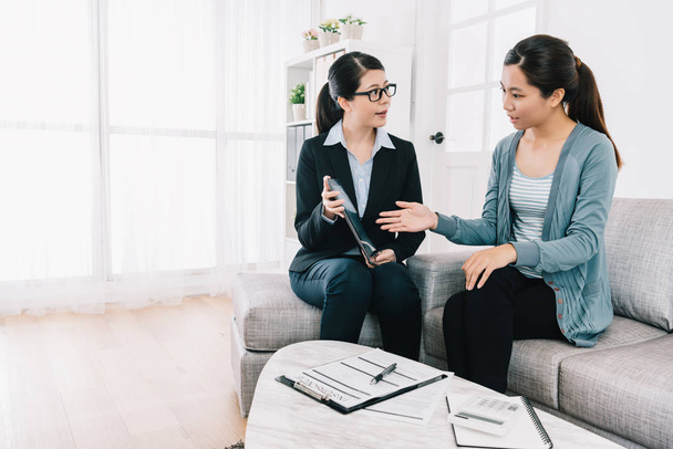 housewife asking the questions about the insurance plan on the tablet to the businesswoman. accountant doing contract work in home office. meeting at home concept. - Photo, Image