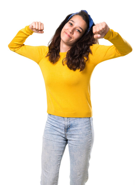 Молода дівчина з жовтим светром і блакитною банданою на голові святкує перемогу і здивована успіхом на ізольованому білому тлі
 - Фото, зображення