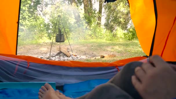 Une femme dans une tente boit du thé chaud. La bouilloire est chauffée sur le feu devant elle
 - Séquence, vidéo