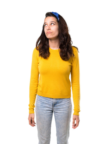 Young girl with yellow sweater and blue bandana on her head stand and looking up with serious face on isolated white background - Фото, зображення