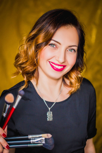 Portrait of smiling makeup artist who keeps makeup brush in her hand - Zdjęcie, obraz