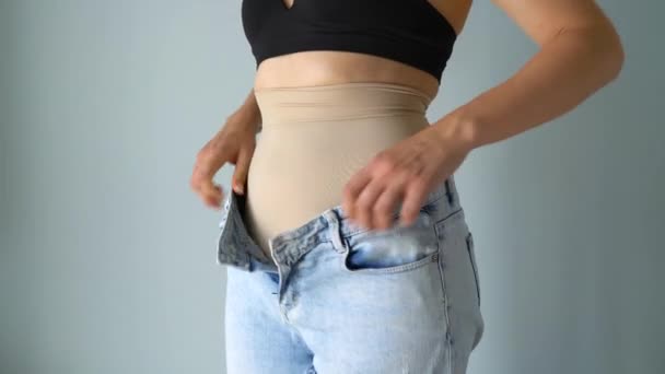 Woman hides the imperfection of the figure under the pulling corrective underwear. Wearing jeans on top, jeans fit perfectly on the figure. Concept of aspiration for a perfect body - Footage, Video