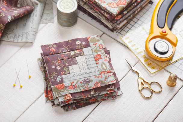 Patchwork log cabin blocks, stack of blocks, sewing accessories on white wooden surface - 写真・画像