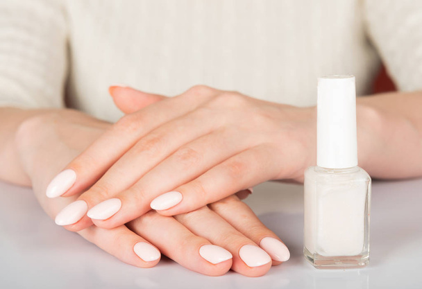  woman's hands with white nail varnish bottles. Nails care - Фото, изображение