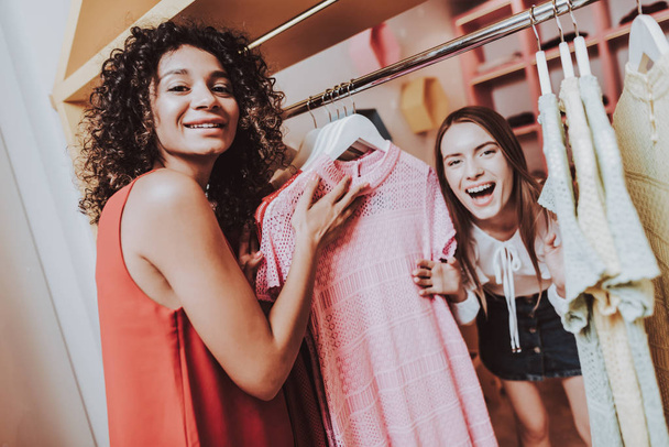 Two Young Girls Have Fun in Dressing Room in Shop. Woman on Shopping. Shopping in Modern Mall. Shopping Concept. Girl in Red Dress. Dressing Room in Boutique. Happy Women. Modern Boutique. - Photo, image