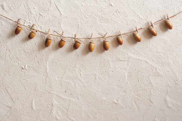 Autumn composition. Acorn with clothespins on clothes line rope. Wooden pegs. Flat lay, top view, copy space. - Photo, image