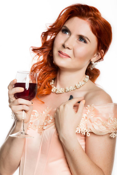 Young redhead woman drinks a red wine with a happy face and smiling with a confident smile. white background. - Fotografie, Obrázek