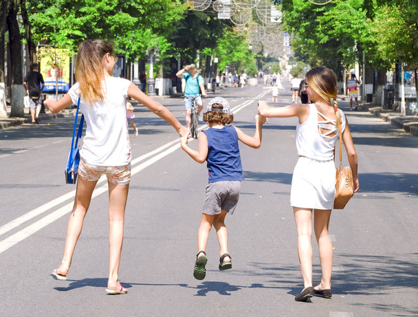 Little Children and Teenagers Holding Hands and Walking Outdoors. Back view. Friendship and love concept - Фото, зображення