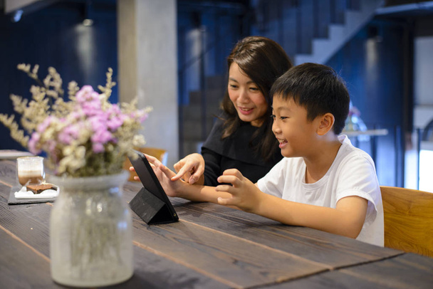 Молодая мать использует планшет с сыном в кафе
 - Фото, изображение