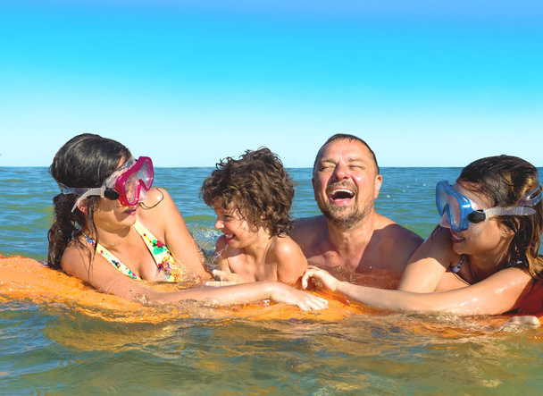ευτυχισμένη οικογένεια με παιδιά κολυμπά και διασκεδάζει στη θάλασσα σε φουσκωτό στρώμα. χαρούμενη φιλική έννοια της οικογένειας - Φωτογραφία, εικόνα