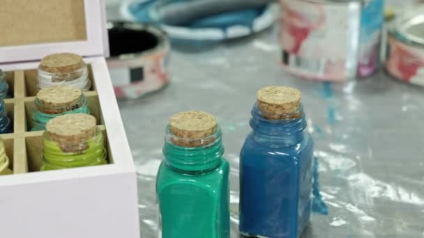 Ręce palcami jar i buteleczek z farbą, wybierając odpowiedni kolor w wazonach - Materiał filmowy, wideo