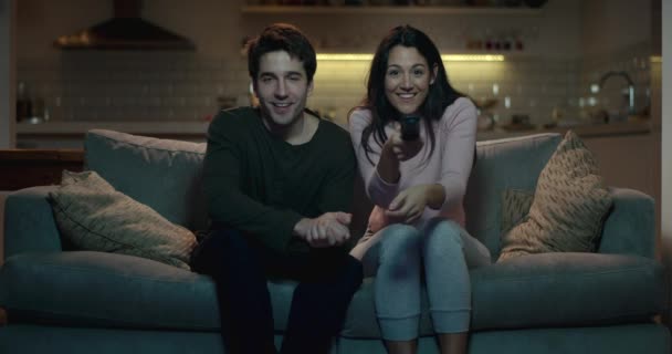 junges Paar, das nachts auf einem Sofa sitzt und sich auf seinen Lieblingsfilm oder seine Fernsehshow vorbereitet - Filmmaterial, Video