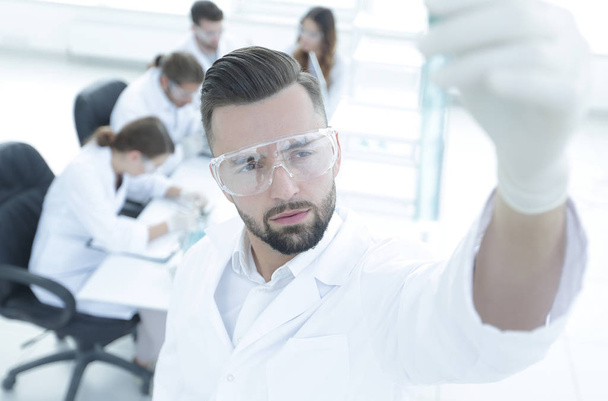 image is blurred. young scientist holding tube with the reagents - Photo, Image