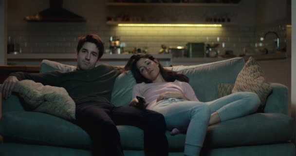 Entspanntes Paar auf der Couch in einem gemütlichen Wohnzimmer vor dem Fernseher. - Filmmaterial, Video