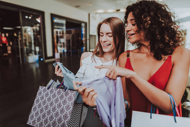 Young Women with Packages Shopping in Modern Mall. Shopping Concept. Girl in Red Dress. Woman in White Shirt. Black Friday Concept. Happy Women. Holding Packages. Pack from Mall in Hands. - Фото, изображение