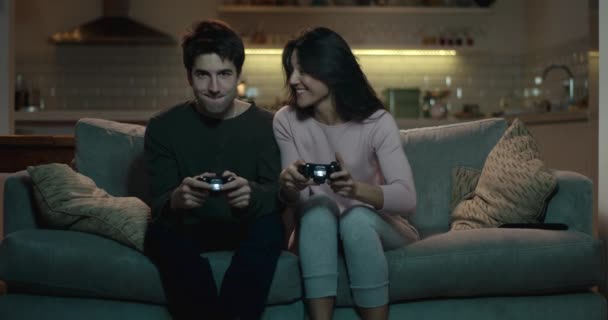 Competitive couple push and shove each other as they play a video game at home - Filmati, video