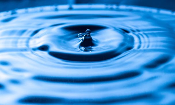 брызги воды в стакане синего цвета - Фото, изображение