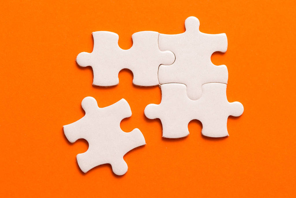 Quatro detalhes brancos de quebra-cabeça no fundo laranja
. - Foto, Imagem