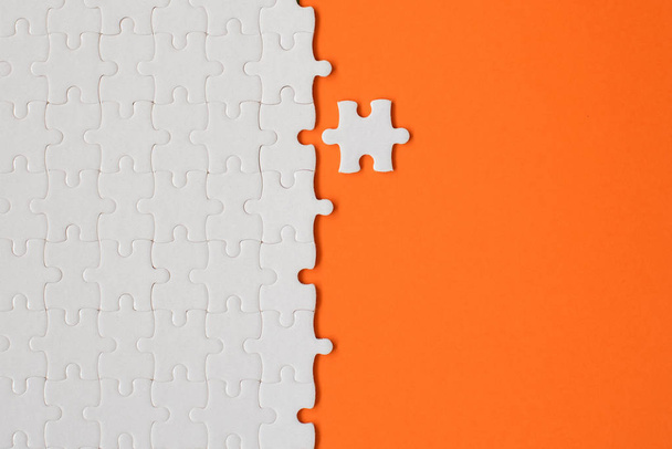 White details of puzzle on orange background. - Foto, Imagen