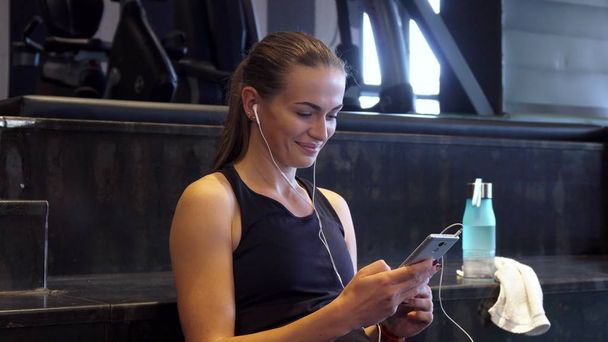 A beautiful girl turns on music in headphones before doing sports - Foto, imagen