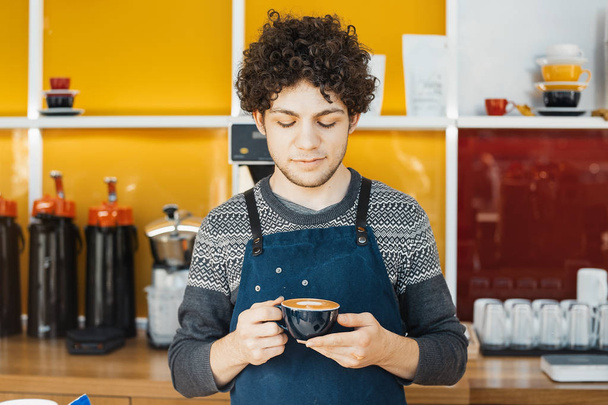 Barista holding coffee cup near bar counter in bright modern cafe. - Fotografie, Obrázek