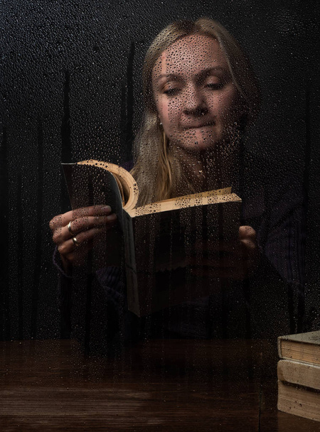 Naturally beautiful millennial woman reading book at rainy autumn day - Фото, изображение
