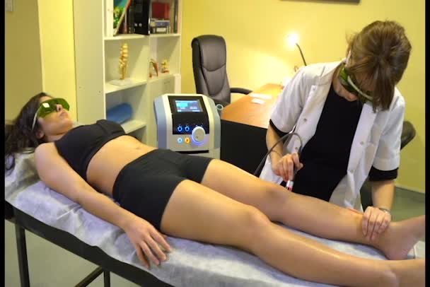 Fisiyoterapist bir kadının dizine yüksek yoğunluklu lazer uyguluyor. Diz kinesiologa fisiatra aplica lazer de alta intensidad BTL rodilla de mujer. - Video, Çekim