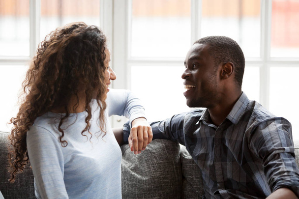 Black couple in love talking sitting on couch at home - Foto, immagini