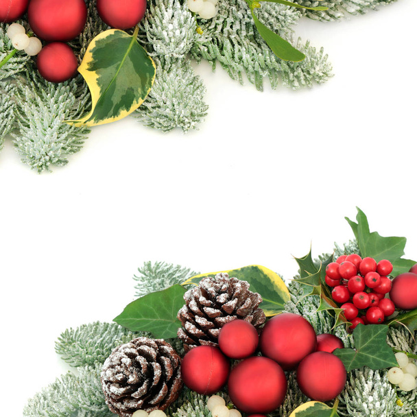 Weihnachten Hintergrund Bordüre mit roten Christbaumschmuck, Stechpalmen, schneebedeckten Fichte Kiefer, Efeu, Tannenzapfen und Mistel auf weißem Hintergrund mit Kopierraum. - Foto, Bild