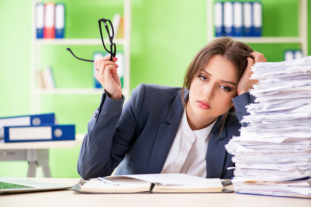 Young female employee very busy with ongoing paperwork - Photo, Image