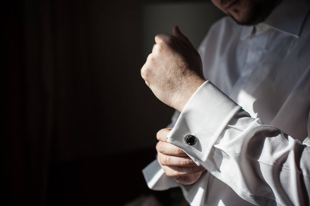 The groom in a white shirt wears a cufflink. - Foto, Bild