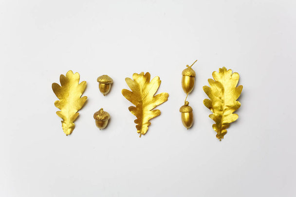 Golden oak leaf and acorn on light grey background. Top view - Zdjęcie, obraz