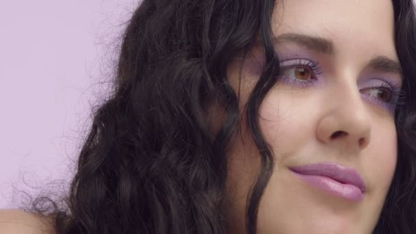 černými kudrnatými vlasy plus velikost modelu s hnědýma očima na lila pozadí s lila make-up - Záběry, video