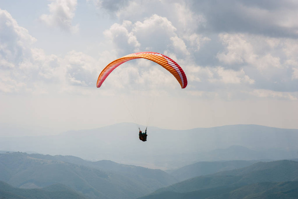 Jedno skrzydło latać nad Dolina górska w słoneczny letni dzień. Paralotniarstwo w Karpatach w okresie letnim. - Zdjęcie, obraz