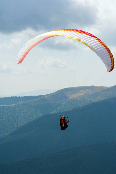 Un parapente survole une vallée de montagne par une journée d'été ensoleillée. Parapente dans les Carpates en été
. - Photo, image