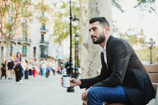 young man holding a coffee cup drink sitting on a bench - Fotoğraf, Görsel