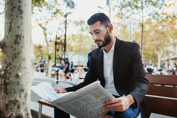 若い男がベンチで新聞を読んで - 写真・画像
