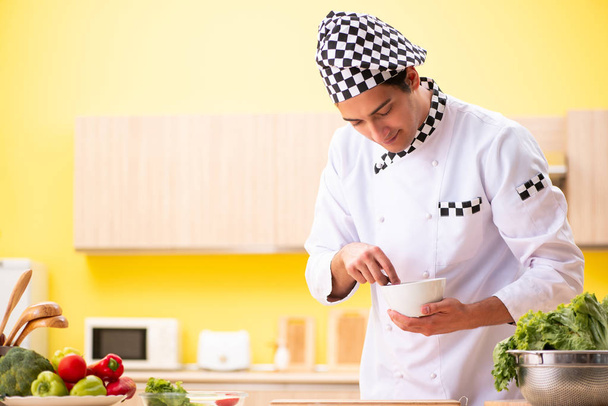Jonge professionele kok bereidt salade thuis - Foto, afbeelding