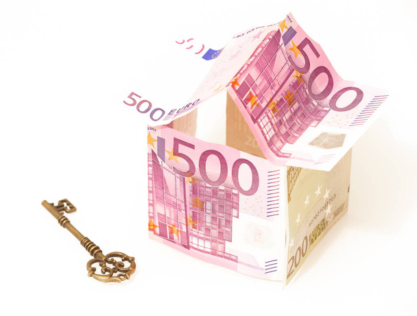 euro, symbol kredyt mieszkaniowy. Europejskich pieniędzy w kształcie domu i klucz na białym tle - Zdjęcie, obraz