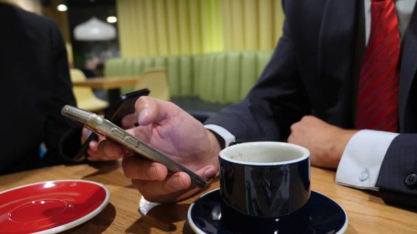 Business woman and businessman hands texting, sending sms on smartphone and drinking coffee in cafe. - Foto, afbeelding