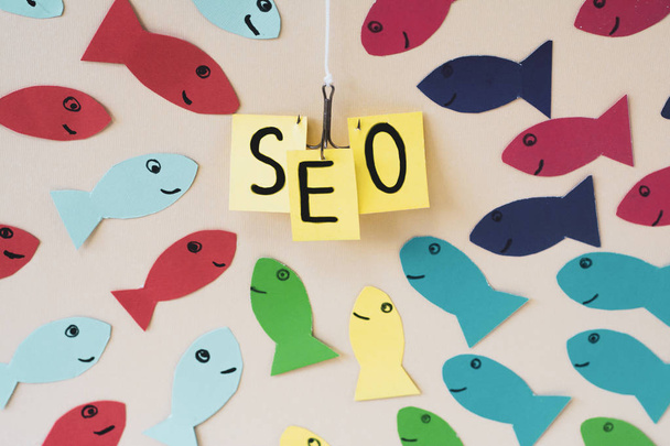 SEO, Search Engine Optimization ranking concept. Group of fishes rushes to fish hook with banner SEO. - Photo, Image