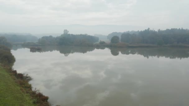 霧の秋の朝にスロベニア語の田舎の美しい反射湖のショットをパン - 映像、動画