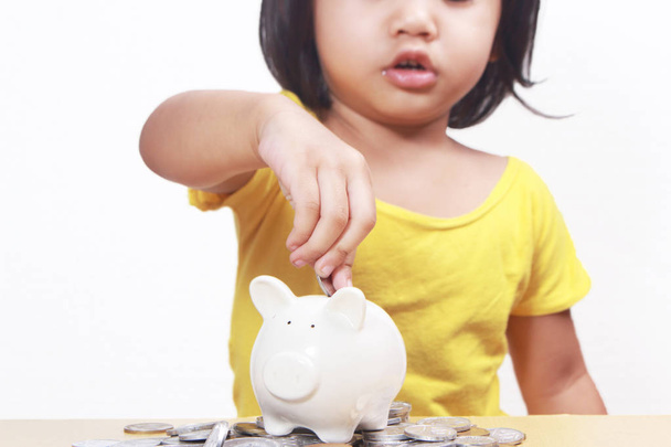 Business economic finance investment concept. Cute little Asian baby girl saving money in her piggy bank - Photo, Image