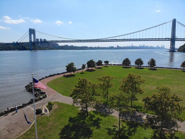 ジョージ ・ ワシントン橋、ニュージャージー州フォート ・ リーの背景にアメリカの国旗の空撮。ジョージ ・ ワシントン橋は、ニューヨークのマンハッタンにニュージャージーを接続するハドソン川に架かる吊り橋です。. - 写真・画像